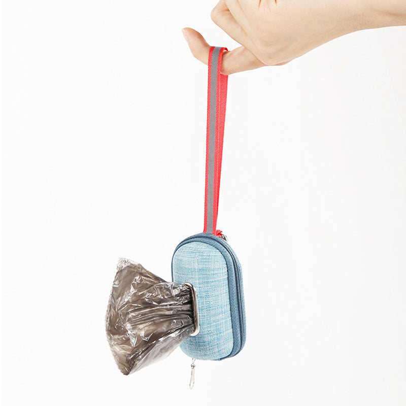 TidyTrail poop-bag dispenser held by its finger loop strap, in-use view